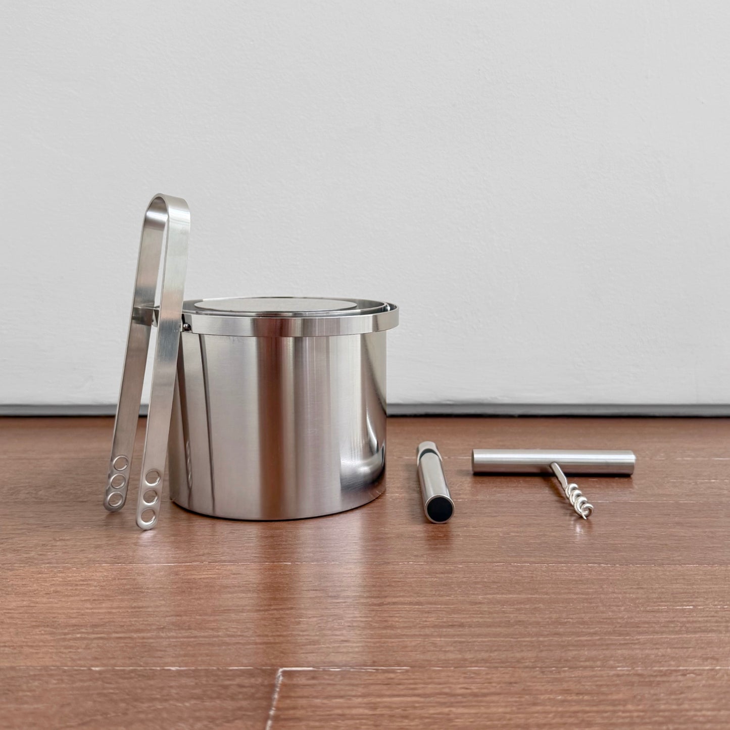 Stelton Stainless Steel Bar Set featuring a polished metal ice bucket with tongs, a bottle opener, and a corkscrew, showcasing vintage Scandinavian design.