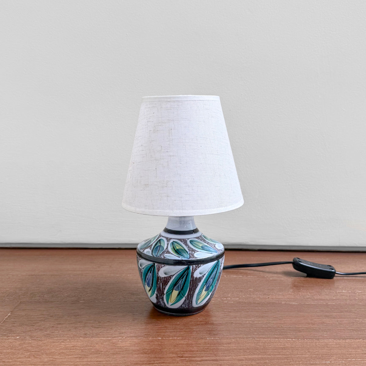 Swedish Botanical Table Lamp vintage ceramic lamp with sgraffito leaf motif and new fabric shade on a wooden surface
